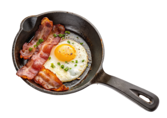 Rustic breakfast in skillet with crispy bacon and sunny side up egg garnished with green herbs