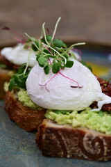 Avocado Toast with Poached Eggs, Bacon and Microgreens – Gourmet Breakfast Close-Up