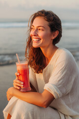 young woman drinking juice on the beach