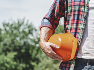 Attractive man, hard hat and work clothes. Labor day. Front view, close up. Sunny day, Labor and...
