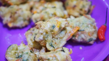 A plate of crispy Indonesian vegetable fritters (bakwan goreng) served with red chili peppers