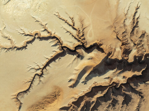 Aerial view of deep shadows accentuate the sinuous curves carved into the arid landscape, revealing an intricate network of canyons, Tsondab Valley, Khomas, Namibia.