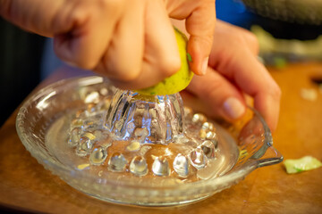 A vivid macro shot capturing a woman slicing a fresh lemon and squeezing its juice over a colorful...
