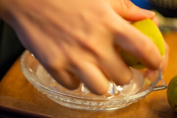A vivid macro shot capturing a woman slicing a fresh lemon and squeezing its juice over a colorful...