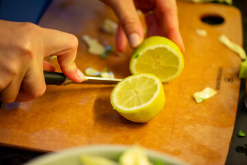A vivid macro shot capturing a woman slicing a fresh lemon and squeezing its juice over a colorful salad, highlighting citrus texture and freshness in culinary action.