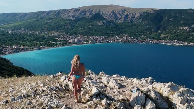 Panoramic Aerial Shot Beautiful Young Woman in Bikini Hiking Trail Leading From the Beach in Baska to the Bag Mountain Top, Azure Water in the Bay by the Beach in Baska on Krk Island, Croatia