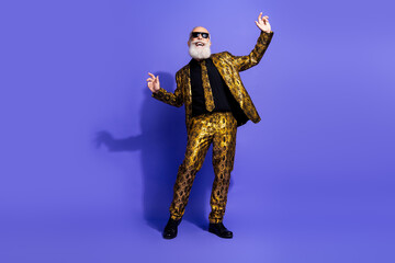 Elderly man in vibrant gold pattern suit dancing stylishly on purple background