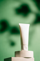 A white tube of soothing face cream against a green background, ideal for use in skincare ads,...
