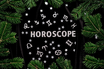 Abstract background with the inscription Horoscope on a black velvet background with fir branches.