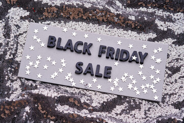BLACK FRIDAY SALE sign on a sparkling silver sequin background.
