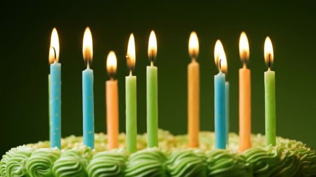 Lit birthday candles stand on a green frosted cake against a dark green backdrop.
