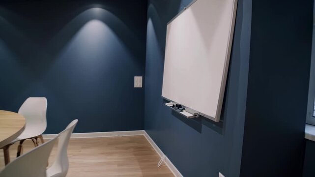 Modern Meeting Room: Crisp architecture meets design. A bright white interactive board is installed on an eye-catching blue wall in a meeting room with round table.
