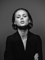Black and white portrait of confident woman with short hair wearing dark jacket, sharp gaze and...