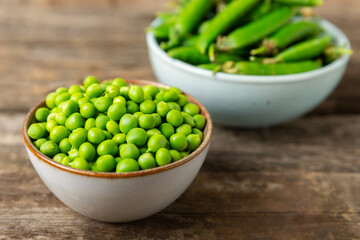 Fresh green pea pods with green peas on a wooden background. Sweet green peas. Green pea beans vegetables. Vegan. healthy vegetable. Copy space