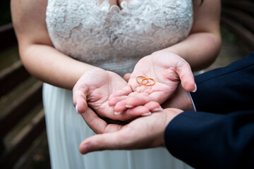 Una pareja de recién casados juntando las manos y enseñando los anillos de oro