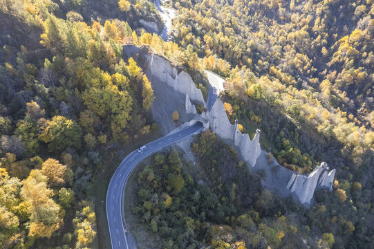 Aerial view of a winding road cutting through the landscape next to the Pyramides d'Euseigne under the soft autumn light, H&Atilde;&copy;r&Atilde;&copy;mence, Valais, Switzerland.