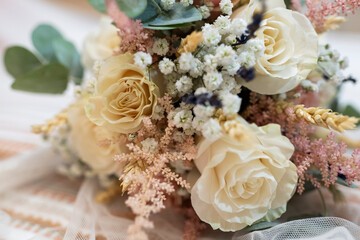Ramo de novia de rosas y florecillas, posado e el suelo y de fondo los novios