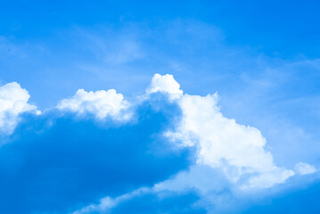 Bright cumulus clouds in a clear blue sky on a sunny day.