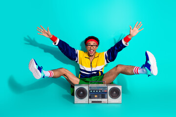 Energetic young man with a retro boombox in vibrant activewear on a bright teal background...