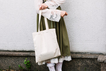 Young white woman holding black eco bag on arm shoulder or hand, street wall at background. city living female going on shopping to grocery store