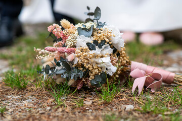 Ramo de novia de rosas y florecillas, posado e el suelo y de fondo los novios