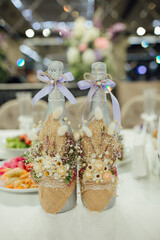 Rustic wedding champagne bottles decorated with burlap, dried flowers, and lavender bows. Elegant...