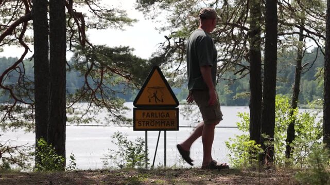Alvkarleby, Sweden A man walks past the Dala River and a warning sign in Swedish saying: Danger Strong Currents. 