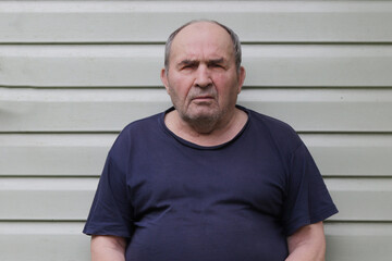 Portrait of an old man near the wall.