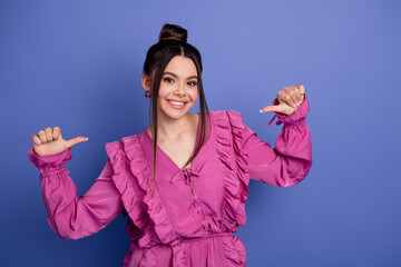 Stylish young woman wearing a pink outfit posing confidently against a purple background with a...