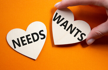 Wants and Needs symbol. Concept word Wants and Needs on wooden hearts. Businessman hand. Beautiful...