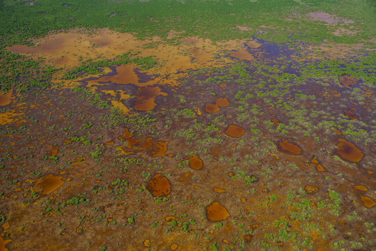 Aerial view of a tapestry of wetlands and scattered pools reflecting the sky's hue, interwoven with patches of green vegetation, Merida, Yucatan, Mexico.