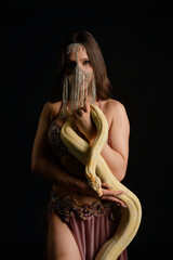 Woman poses elegantly in studio while playfully interacting with a snake