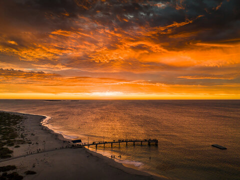 Aerial view of the pier stretching into the tranquil ocean under a fiery sunset sky, Western Australia, Western Australia, Australia.
