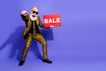 Energetic senior man showcasing vibrant style with a sale sign posing on a colorful background