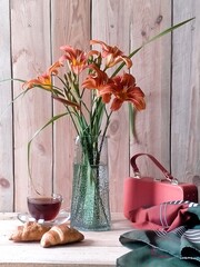 still life with a handbag, headscarf, coffee, croissants and a bouquet of daylilies