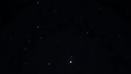 Fototapeta premium A dark sky dotted with bright stars, with a prominent star or planet shining brightly, capturing a peaceful night scene in HD and 4K.