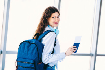 Young female traveler with backpack and boarding pass preparing for a journey at an airport terminal