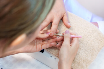Nail spa professional Asian woman performing manicure service with precision on elderly female...