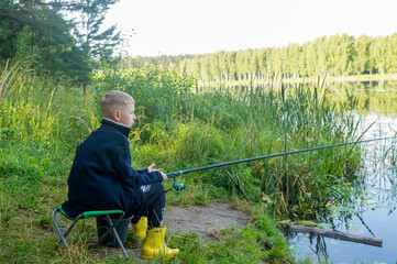 Child fishing alone by peaceful river in summer nature