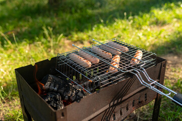  Grilled sausages cooking on open fire during summer picnic