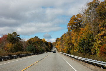 Autumn drive along a scenic highway lined with colorful fall foliage in a rural setting