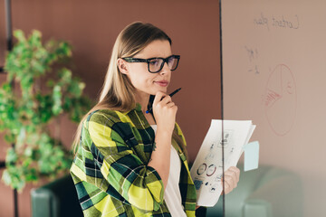 Young woman planning business strategies with charts in a modern office in a casual professional...