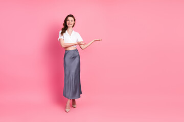 Elegant young woman in casual yet stylish attire posing confidently against a vibrant pink...