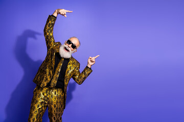 Stylish senior man in a vibrant patterned suit striking a fun pose on a purple background,...