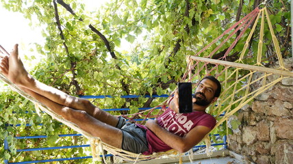 Man Lying in Hammock Holding Up Phone
