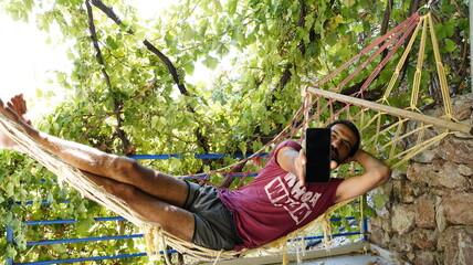 Man Lying in Hammock Holding Up Phone