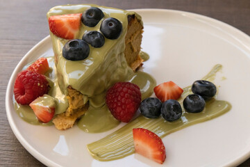Delicious cake slice with matcha glaze and fresh berries