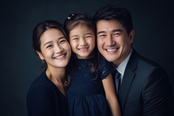 Joyful Asian family portrait with smiling parents and their daughter, celebrating love and togetherness in a professional setting