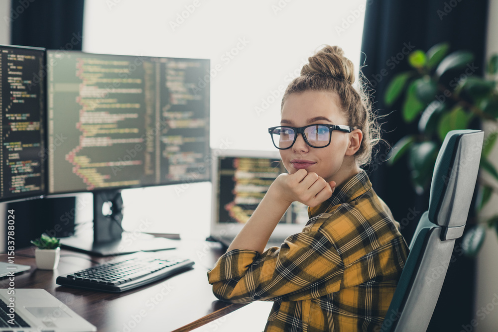 Poster professional woman programmer working remotely at home, writing code on her computer screens in a co