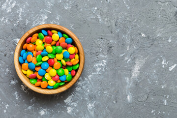 Multicolored candies in a bowl on a colored background. birthday and holiday concept. Top view with...